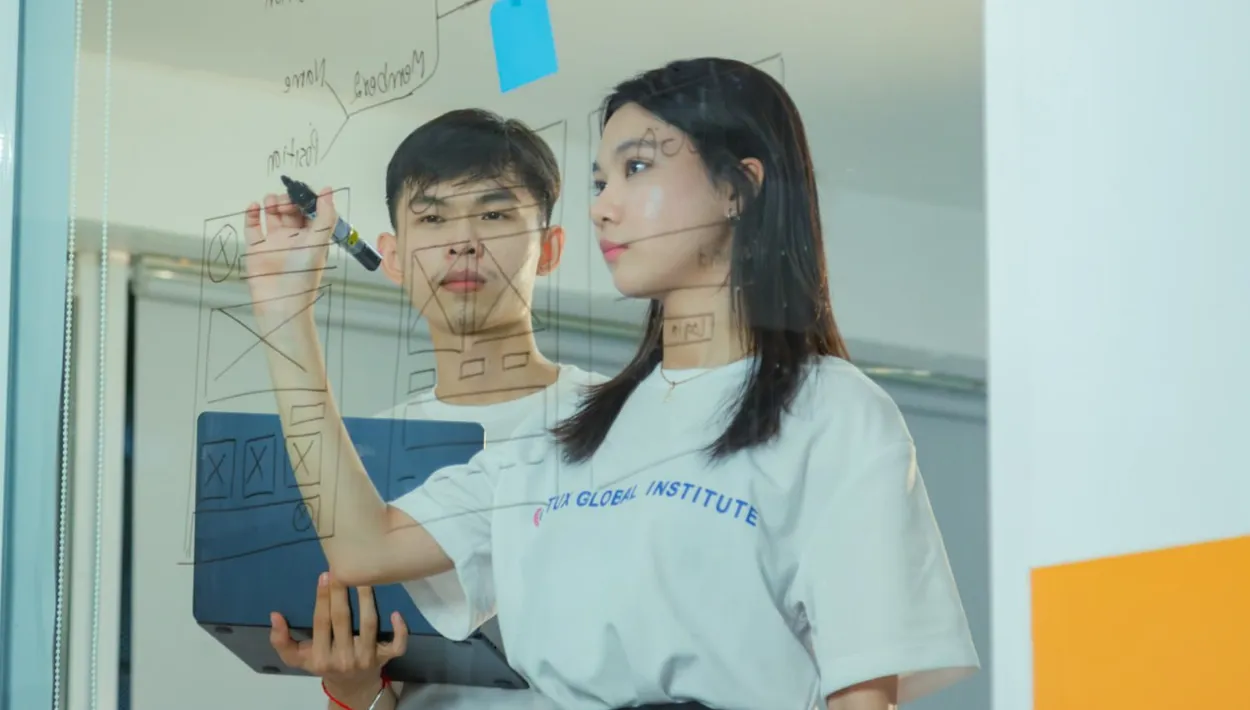 Student drawing wireframe on a transparent whiteboard